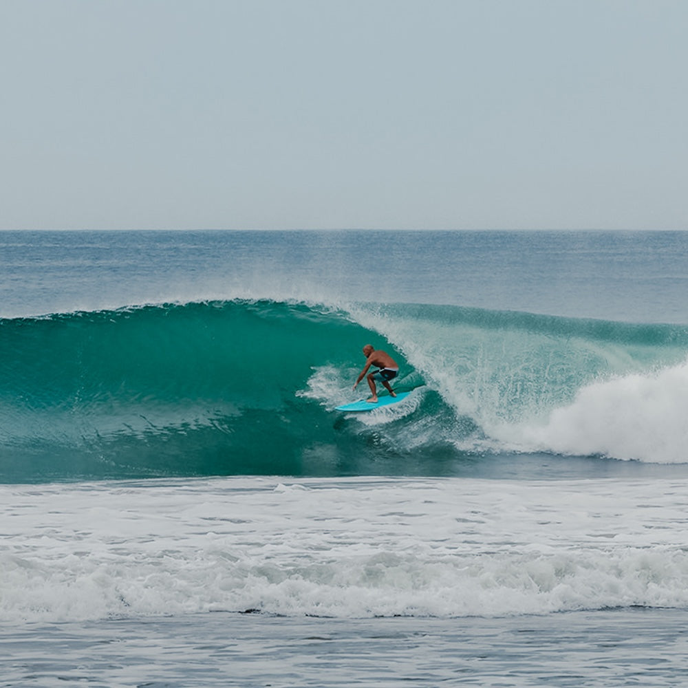 Person surfing on a blue wave in the ocean