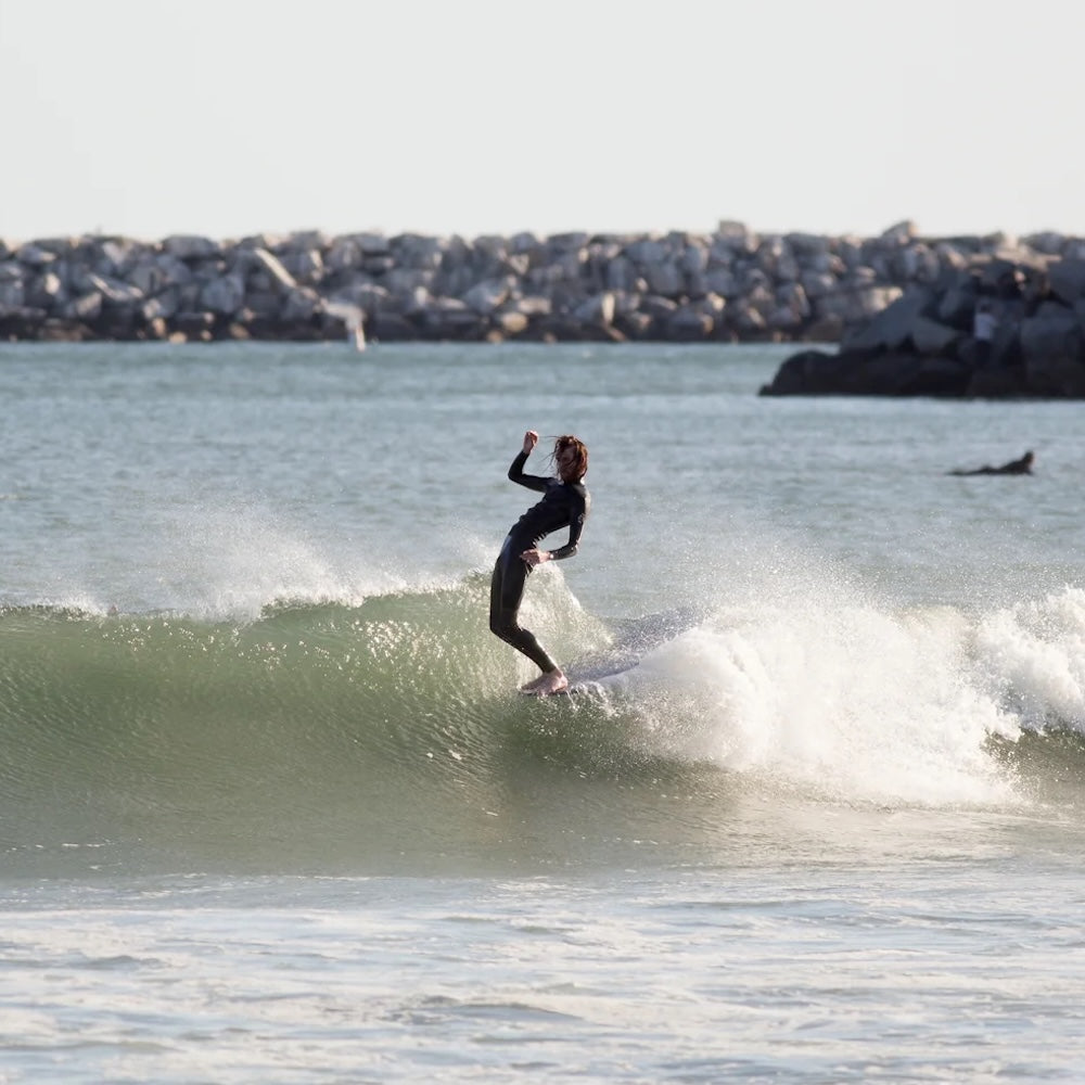 Person surfing on a wave with a cityscape in the background