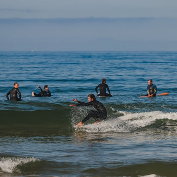 Surfers in wetsuits in the ocean with a clear sky