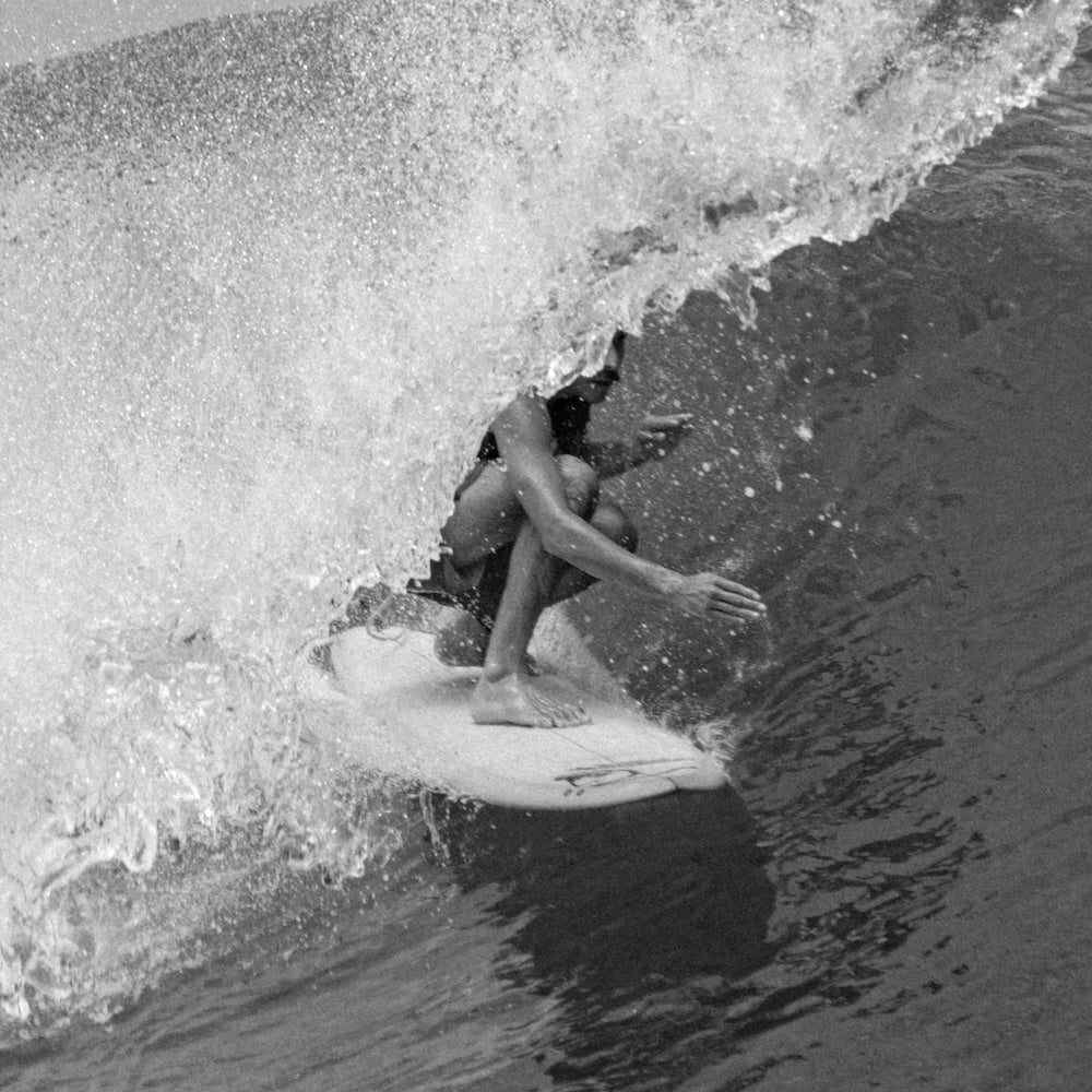 Person surfing on a wave in black and white