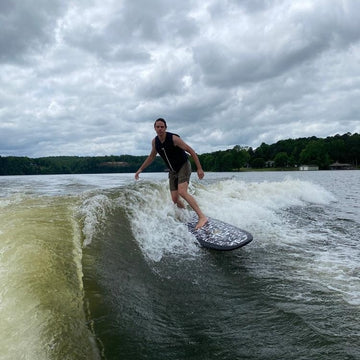 Person wakeboarding on a lake with a cloudy sky