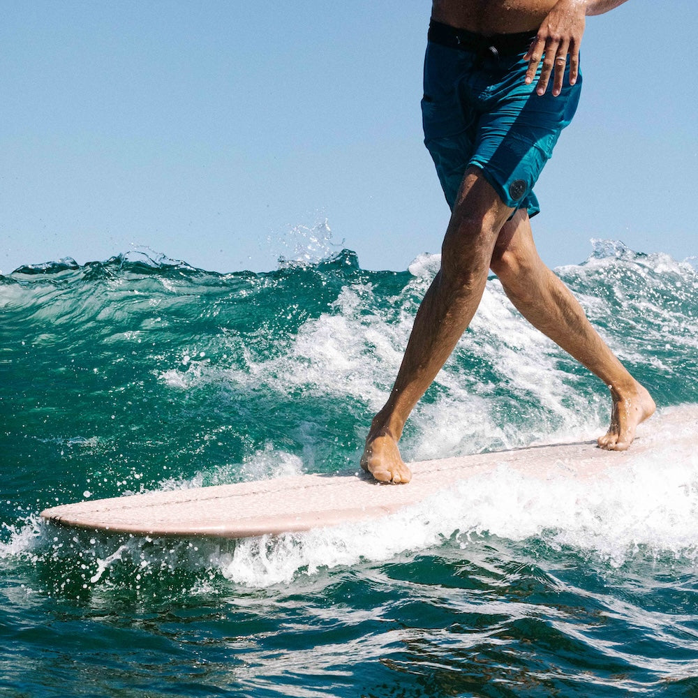 Person surfing on a wave with clear blue sky