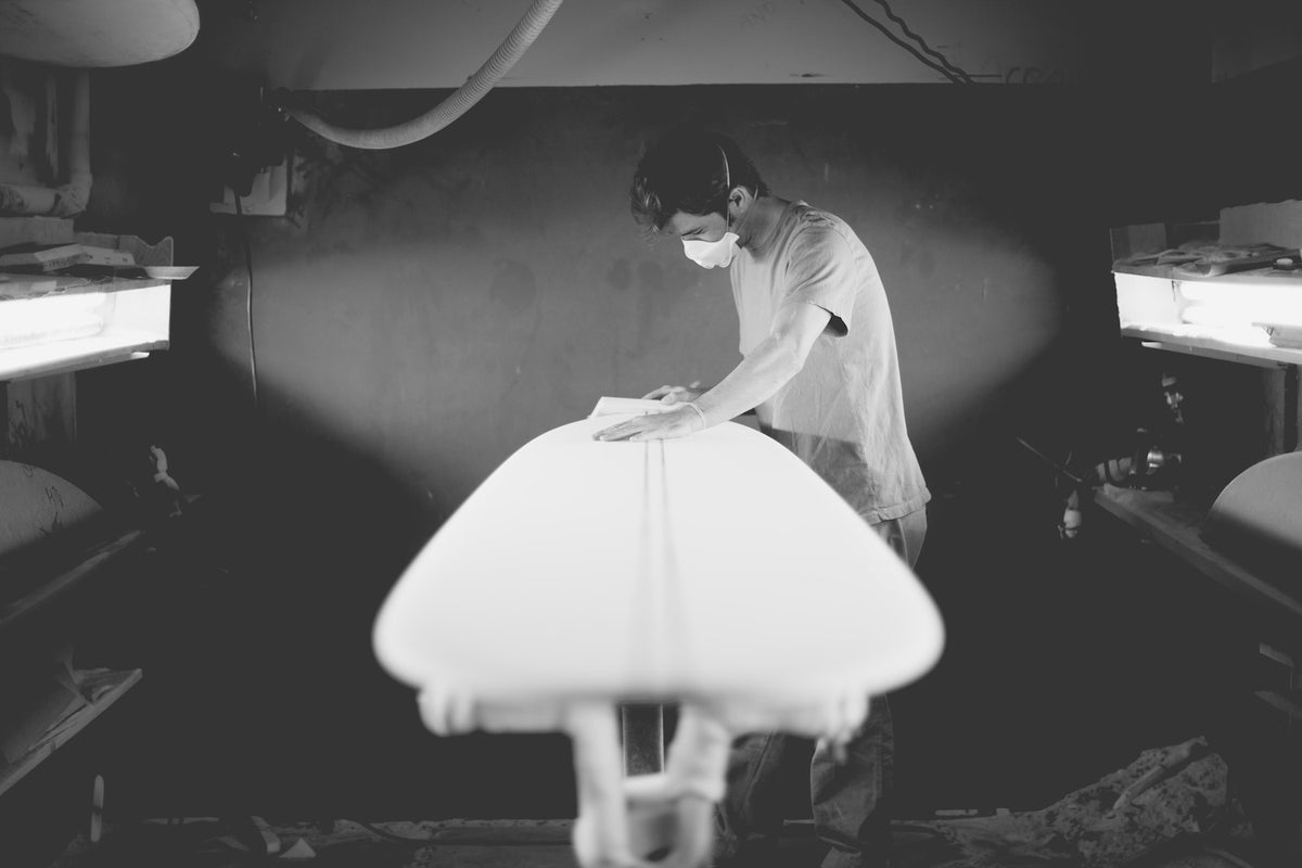 Person holding a surfboard in a dimly lit room