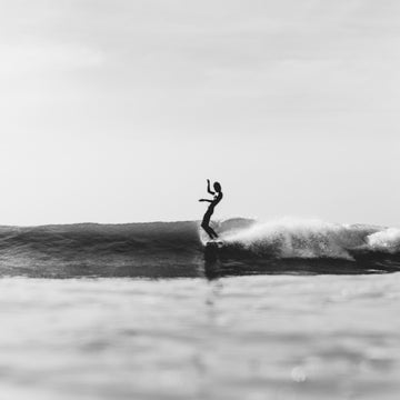 Person surfing on a wave in black and white