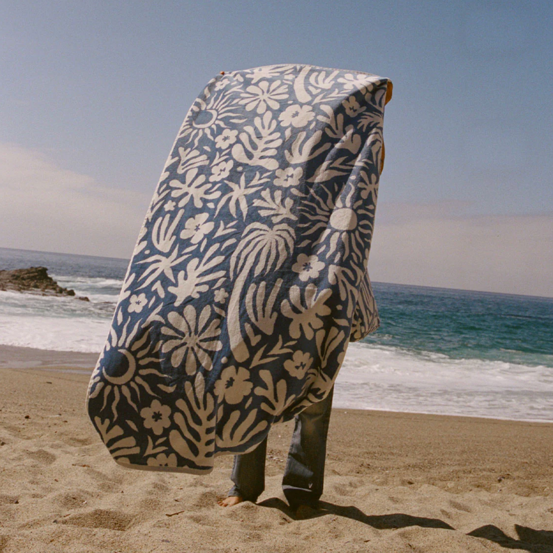 Blue towel with white floral and leaf pattern on a white background