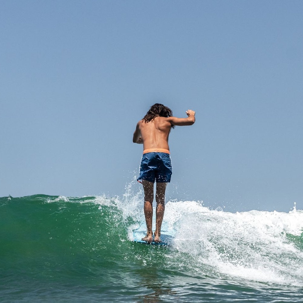 Person surfing on a wave with clear blue sky