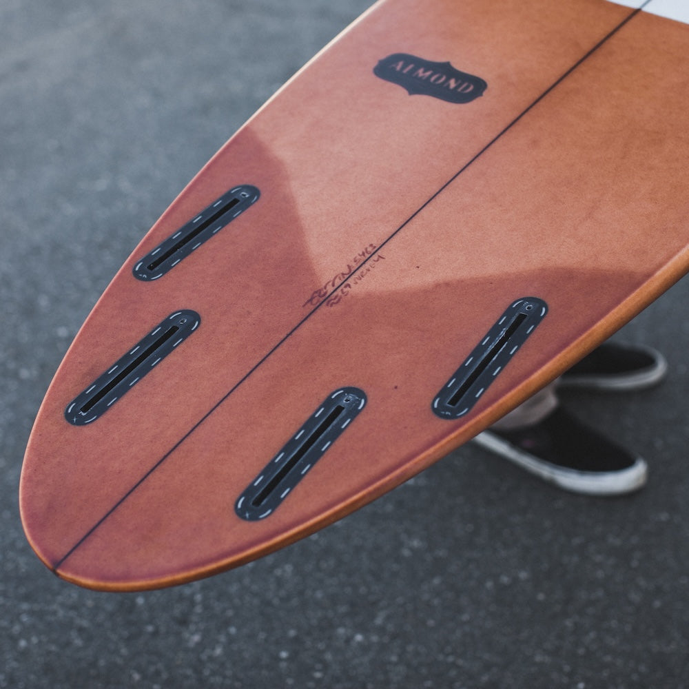 Close-up of a wooden skateboard deck with visible branding on a dark surface