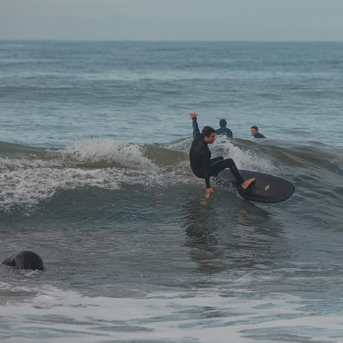 Person surfing on a wave with another person in the water in the background.