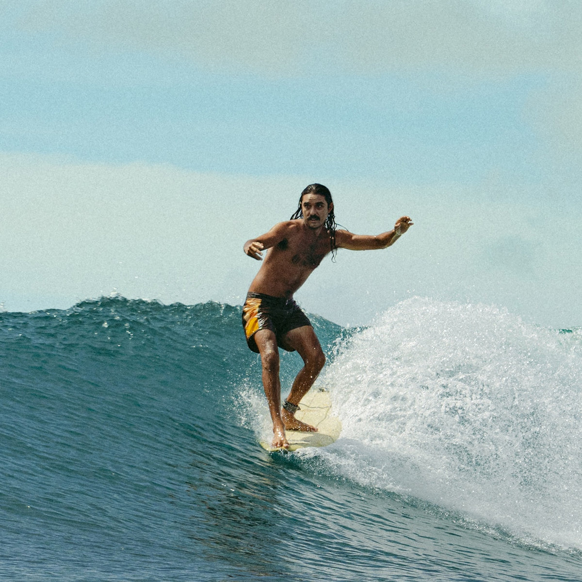 Man surfing on a wave with clear blue sky