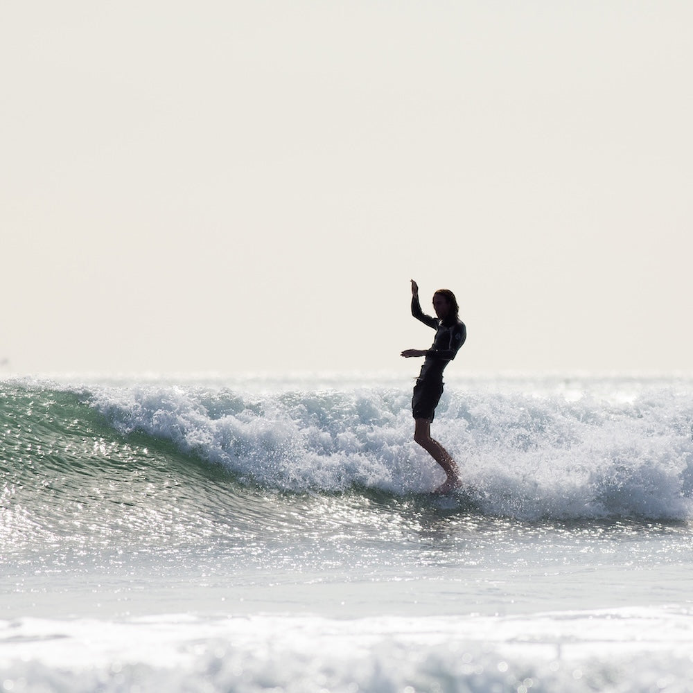 Person surfing on a wave with a clear sky background