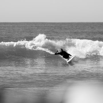 Black and white photo of a surfer riding a wave.