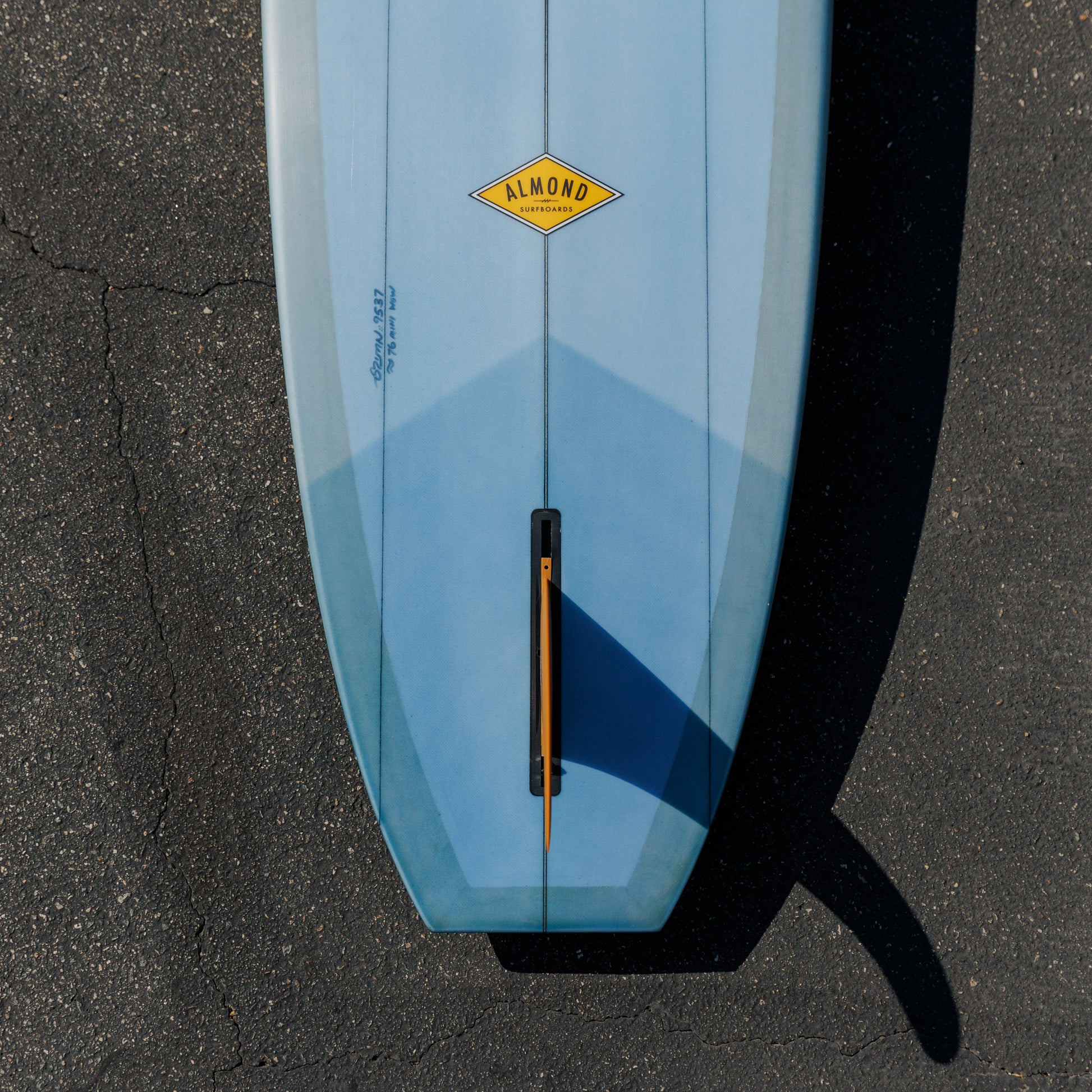 Blue surfboard with a yellow logo on a black surface