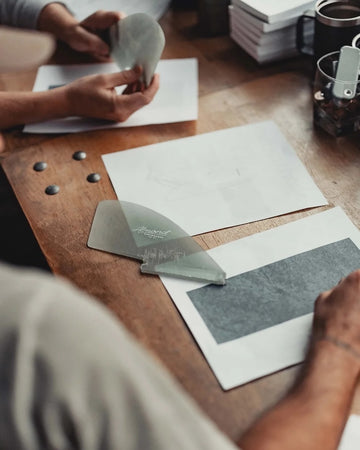 Two people working on a project with tools and papers on a wooden table.