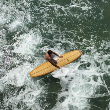 Person on a yellow surfboard in rough ocean waters
